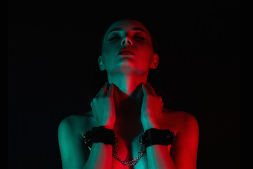 Pretty Girl in handcuffs. Beautiful young Woman in color lights - obrazy, fototapety, plakaty