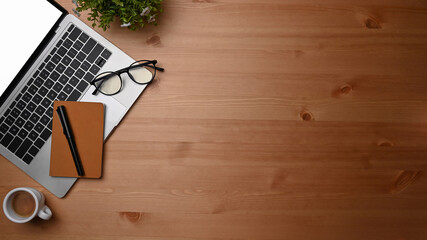 Overhead shot computer laptop, notebook and coffee cup on wooden desk.