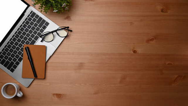 Overhead shot computer laptop, notebook and coffee cup on wooden desk.