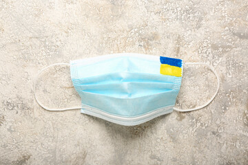 Medical mask with drawn Ukrainian flag on grunge background