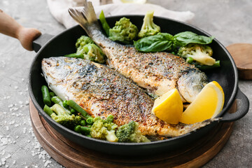 Frying pan with dorado on grunge background