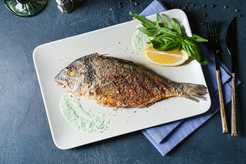 Plate with fried dorado on color background