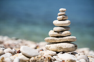 Fototapeta na wymiar Balancing pebble figurine on the seashore. The concept of meditation and pacification. Close-up.