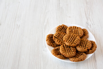 Homemade Peanut Butter Cookies on a plate on a white wooden background, side view. Copy space.