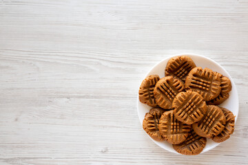 Homemade Peanut Butter Cookies on a plate on a white wooden surface, top view. Flat lay, overhead, from above. Copy space.
