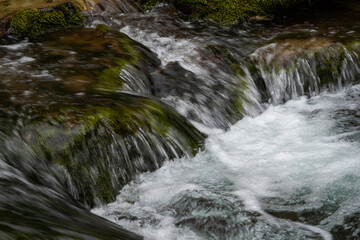 Close-up of the river flow. Mountain river among large stones. Cold water.