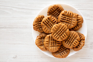 Homemade Peanut Butter Cookies on a plate on a white wooden background, top view. Flat lay, overhead, from above. Space for text.