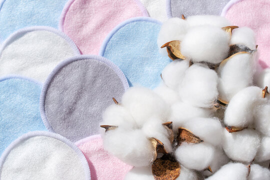 Cosmetic pastel color cotton sponges set in bag on white background with dried cotton flowers