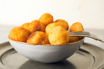 Bowl with fried potato balls on table