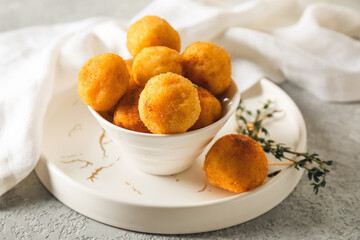 Bowl with fried potato balls on grunge background