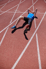 Man with artificial leg laying on the stadium track