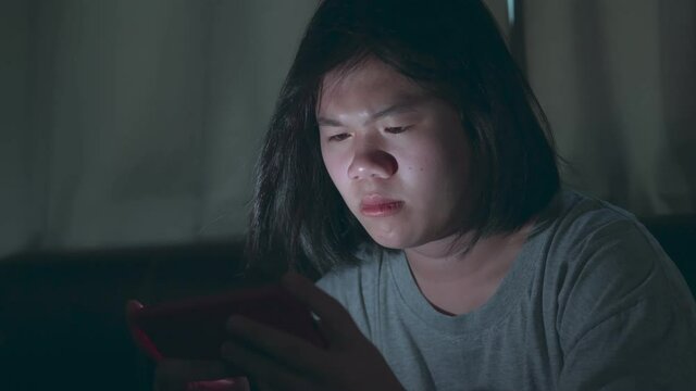 B roll of Asian girl using smart phone or mobile playing games on sofa at home. Young woman using mobile phone on sofa at night. Mobile addiction or insomnia. Young people is phone addiction problem.
