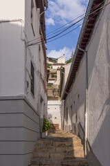 Small narrow street with white houses and abundant greenery in the old European city - 443954087