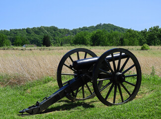 civil war cannon along hancock avenue on cemetery ridge on a sunny day  in the historic gettysburg battlefield  in gettysburg, pennsylvania, with little round top  mountain in the background - obrazy, fototapety, plakaty