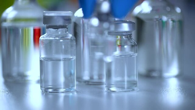 Close-up of scientist slowly put down a vial of vaccine or chemical on a research table with many other vial lying around