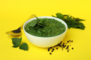 Concept of healthy food with nettle soup on yellow table