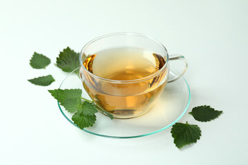 Cup of nettle tea and ingredients on white background