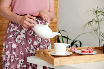  Female hands pouring tea from teapot for morning breakfast.  Сloseup.