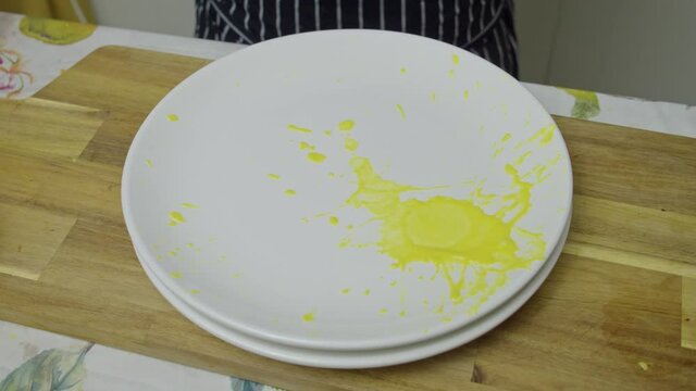 Chef splashes colorful sauces onto white plate. Spin paint technique. Slow motion.