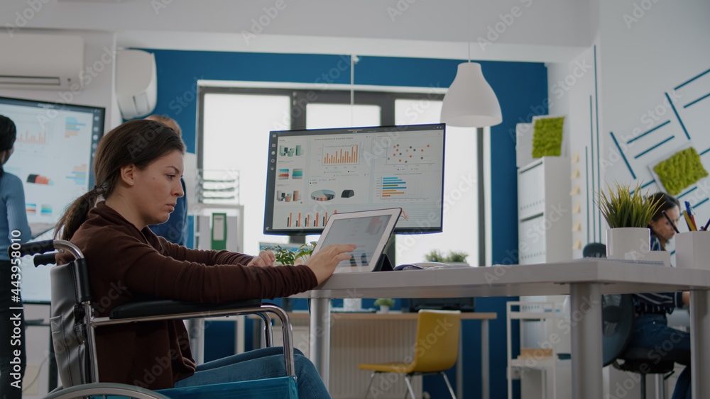 Poster invalid paralysed handicapped woman entrepreneur using computer and tablet in same time checking sta