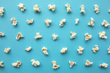 Fototapeta premium Popcorn scattered on blue background. Popcorn pattern. top view.