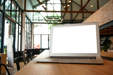 Fototapeta premium Laptop with Mock up blank screen on wooden table in front of cafe space for text. product display computer laptop montage- technology Freelance work concept