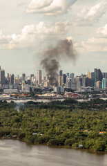 Fototapeta na wymiar Bangkok, Thailand - 04 Jul, 2021 : Plume of smoke clouds from burnt building on fire at some area in the city. Fire disaster accident, Selective focus.