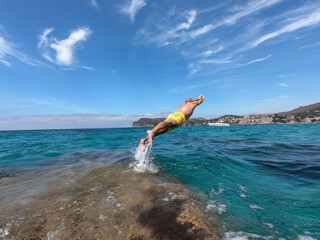 man jumping into the sea on a beach of mallorca concept of summer of holiday