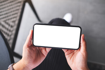 Top view mockup image of a woman holding mobile phone with blank white desktop screen