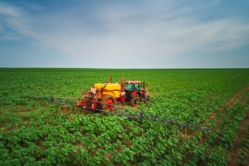 Fototapeta premium Farming tractor plowing and spraying on field