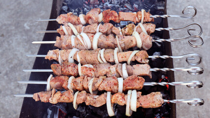Kebabs preparing on a barbecue grill, shashlik preparing on a mangal, marinated meat preparing on a barbecue grill