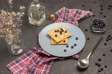 Gray plate with cookies and blueberries on checkered napkin.