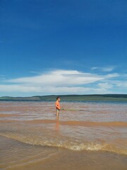 a boy stands in the lake and catches fish
