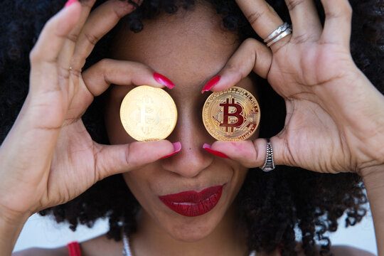 beautiful afro-american woman covers her eyes with a pair of cyber coins. Concept bicoin, internet, online investment