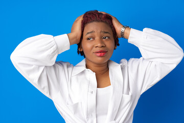 Naklejka premium Young afro woman holding her head against blue background