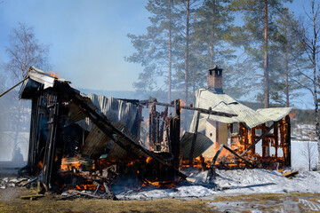 Fototapeta premium Burnt down cabin with flames visible