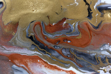 Piles of gold sequins on grey smudges of paint. Abstract pattern.