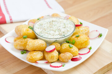 Baked young potato and redishes on a white plate. Blurred bokeh background.