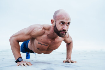 Obraz premium Fitness Model doing Push up on beach from front