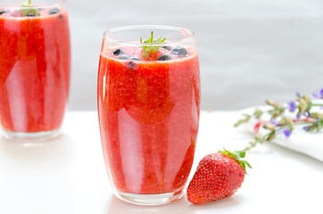 Two glasses of fresh berries fruit and smoothies on white . Blueberries and strawberries.