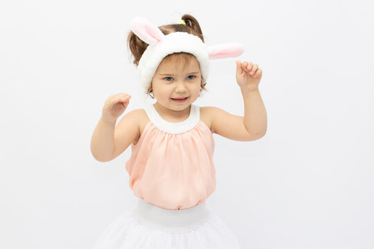 Charming girl in dress and white ears posing as cute bunny on gray background