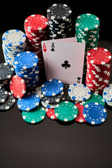 Casino chips and playing cards on dark reflective background