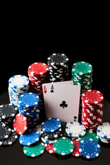 Casino chips and playing cards on dark reflective background