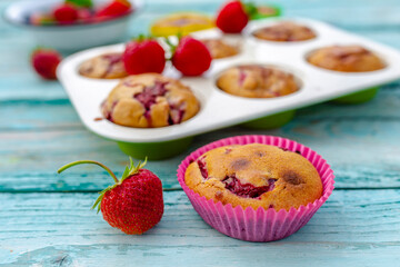 Delicious muffins with fresh strawberry fruit on a wooden background.