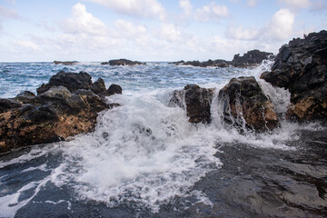 Fototapeta na wymiar Sea with the stones and sand of a beach. Sea waves lash line impact rock.