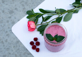 Delicious cocktail of fresh milk with raspberries on a white background in a glass jar with fresh berries and mint. The concept of wellness and weight loss. Natural detoxification
