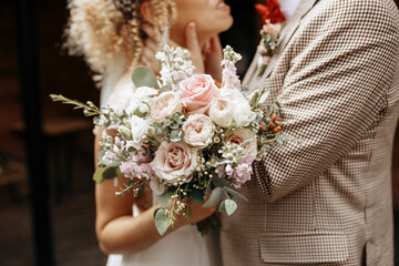 Bride and groom on wedding day hug and show love with a wedding bouquet of rose flowers