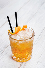 Glass of Negroni cocktail decorated with orange peel on wooden background.