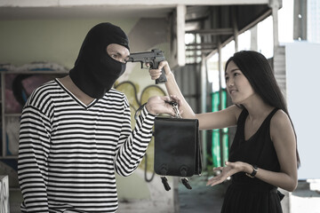 Young woman using gun threaten thief for take back a leather bag.