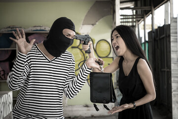 Young woman using gun threaten thief for take back a leather bag.